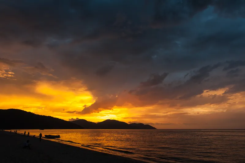Golden sunset over Batu Ferringhi beach, Penang, with the headland in silhouette